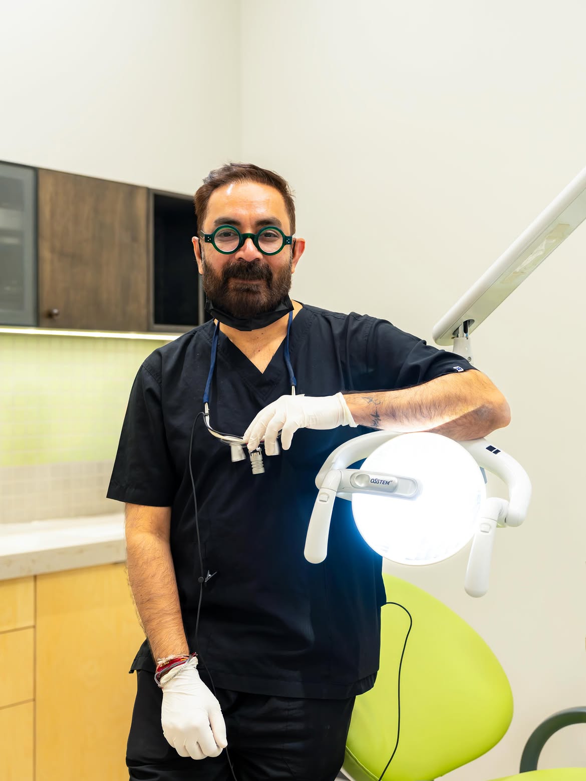 Dr. Mihir Shah standing beside the dental chair and operatory light